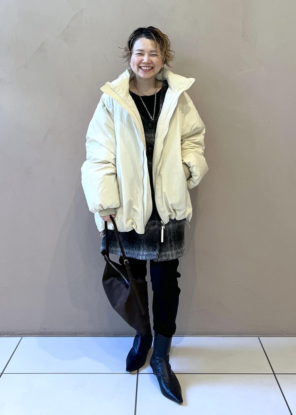 ホワイト系のダウンジャケット/コート、グレー系のジャンパースカート、ブラウン系のショルダーバッグを着用したレディースの秋コーディネートの3枚目の写真