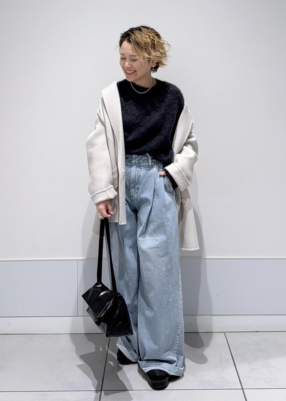 ブラック系のショルダーバッグ、ホワイト系のその他アウター、ブラック系のブーツを着用したレディースの秋コーディネートの3枚目の写真