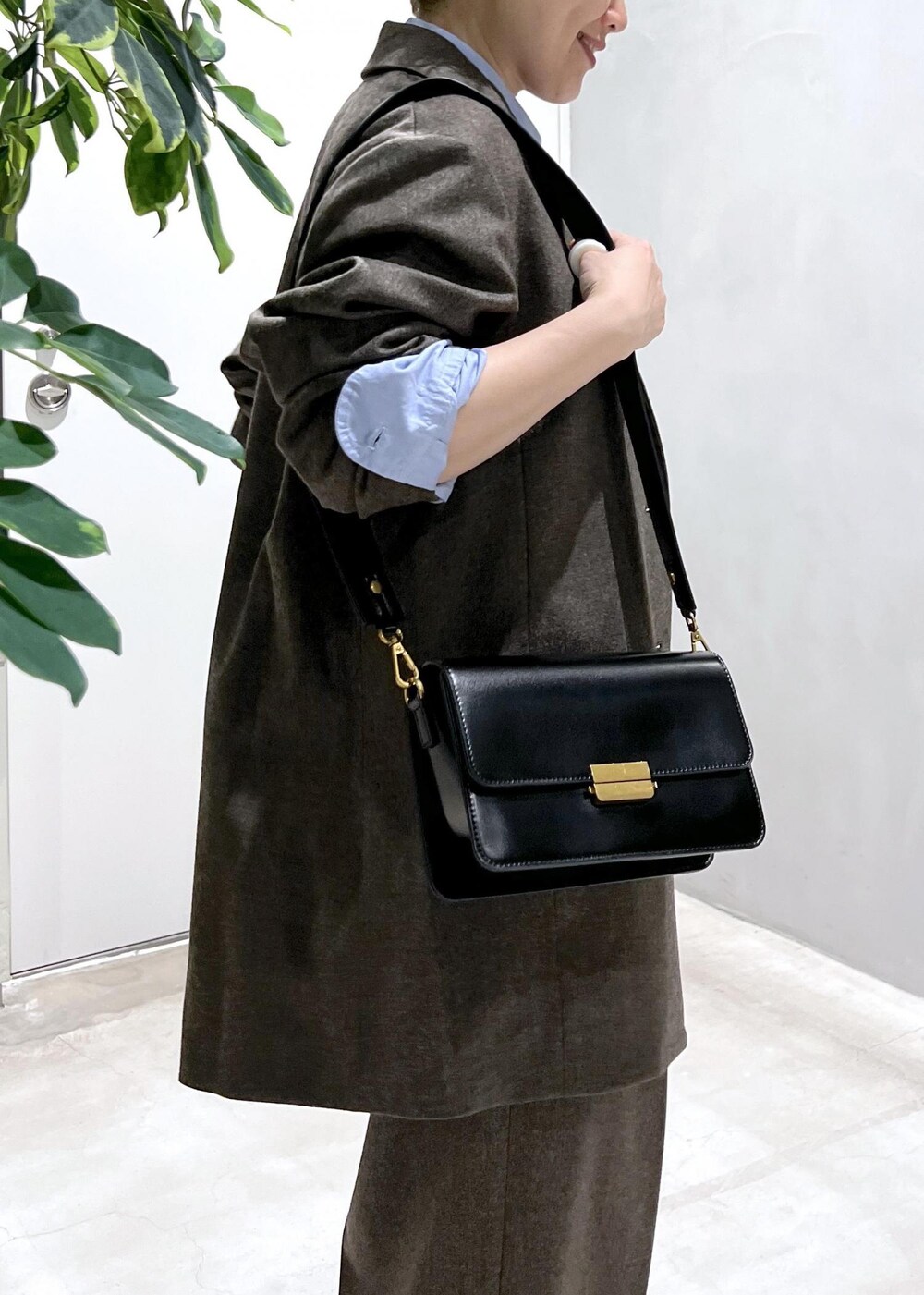 ブルー系のシャツ/ブラウス、ブラック系のショルダーバッグ、ブラウン系のスラックスを着用したレディースの秋コーディネートの9枚目の写真