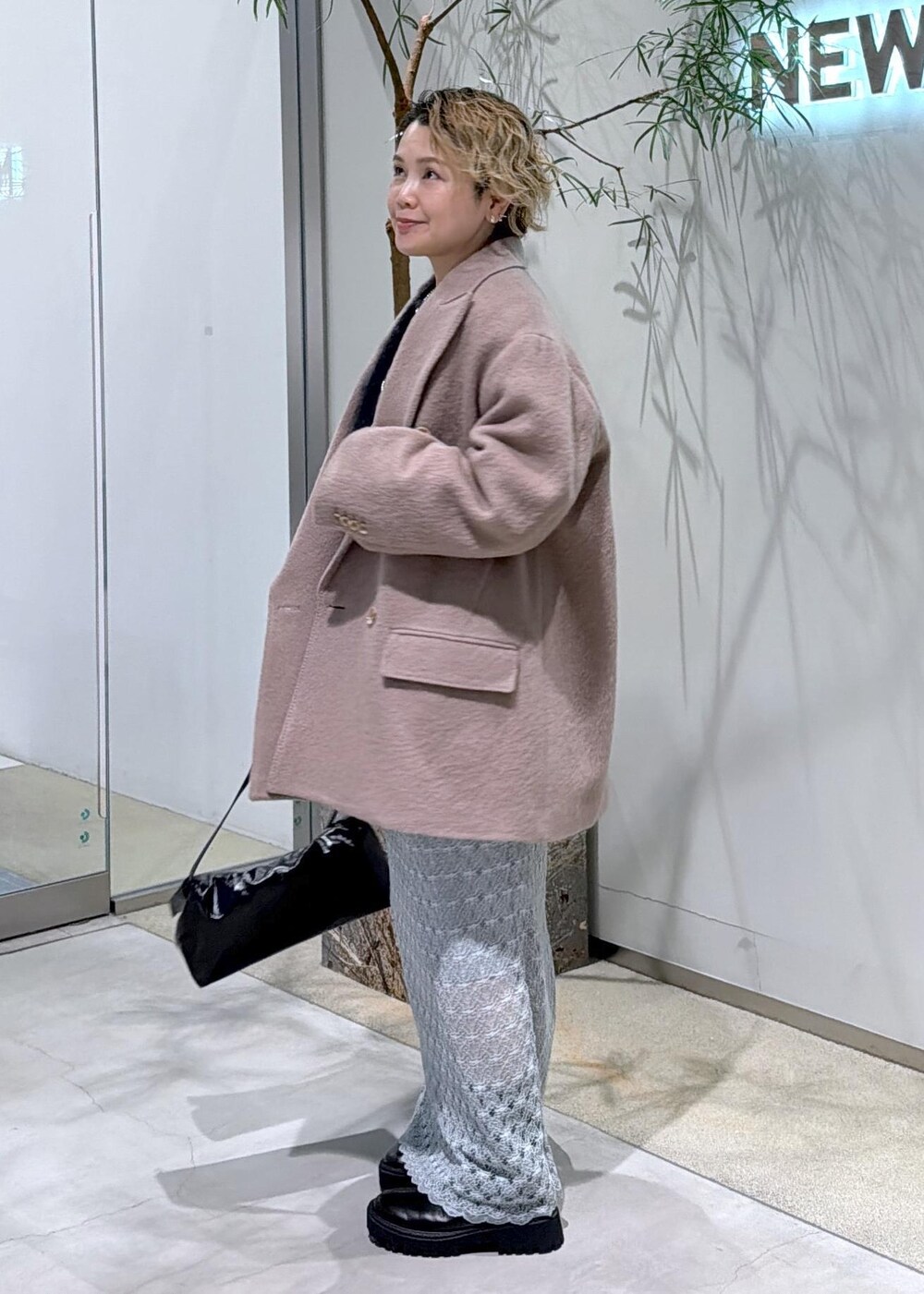 ブラック系のショルダーバッグ、グリーン系のスカート、ブラウン系のチェスターコートを着用したレディースの秋コーディネートの4枚目の写真