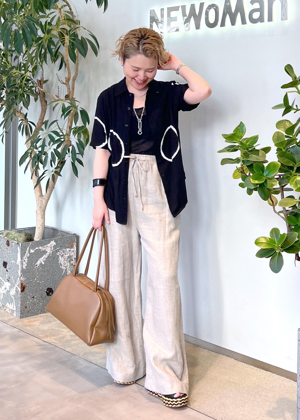 ブラウン系のボストンバッグ、ホワイト系のその他パンツ、ブラック系のサンダルを着用したレディースの夏コーディネートの2枚目の写真