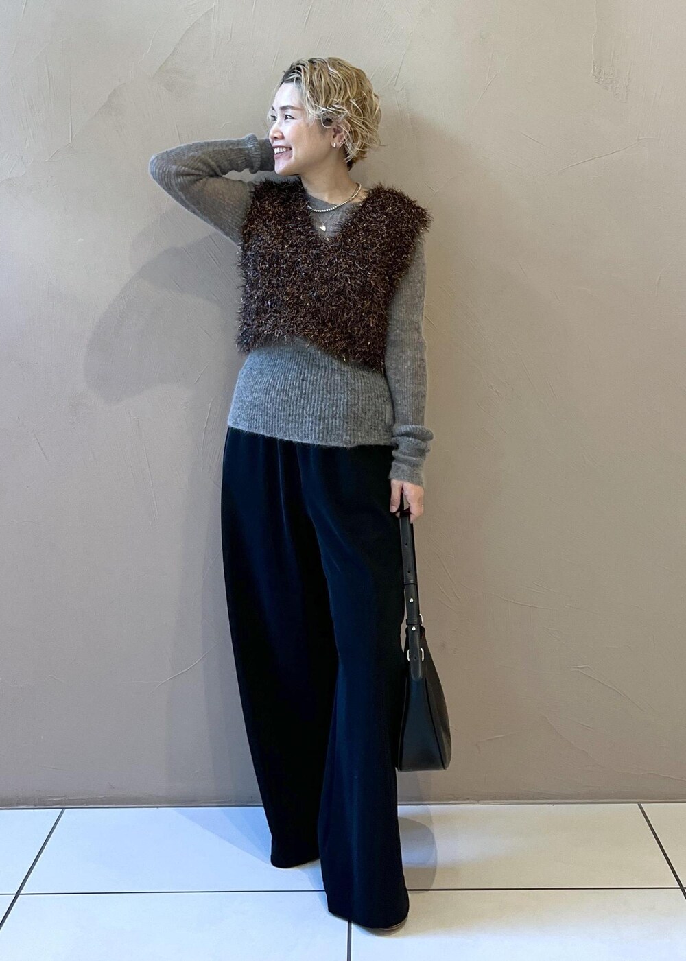 ブラック系のベスト、グレー系のニット/セーター、ブラック系のステンカラーコートを着用したレディースの冬コーディネートの8枚目の写真