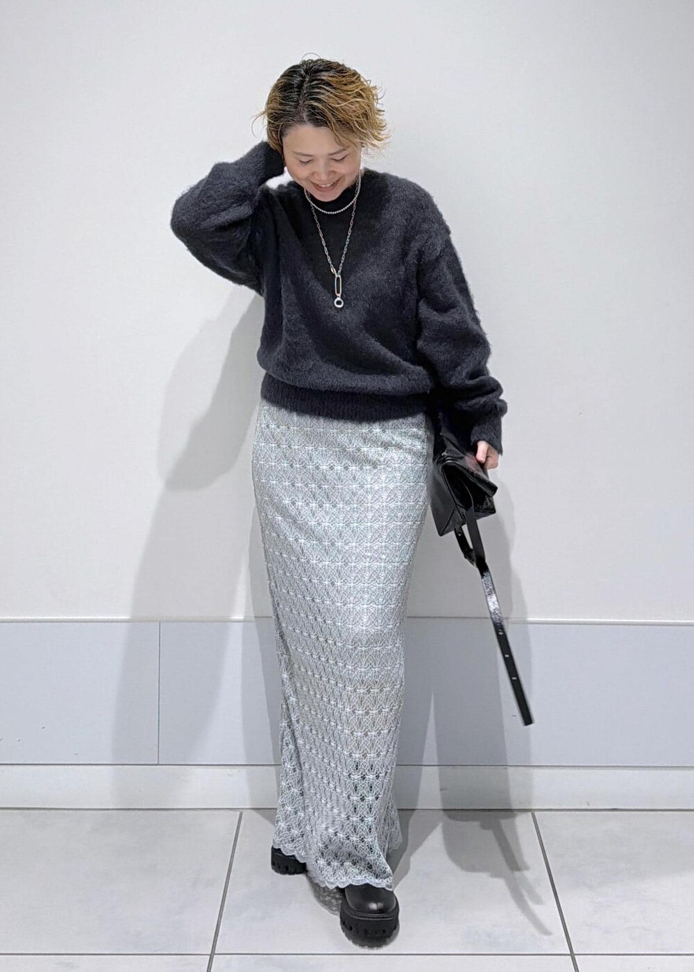 ブラック系のショルダーバッグ、グリーン系のスカート、ブラック系のブーツを着用したレディースの秋コーディネートの2枚目の写真