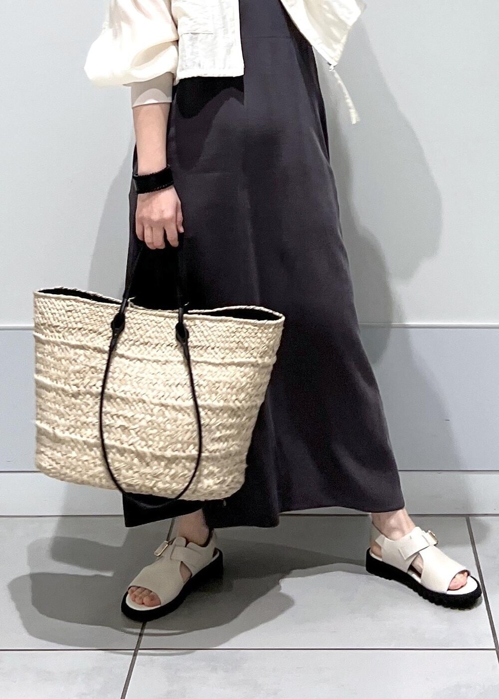 ホワイト系のサンダル、ホワイト系のブルゾン、グレー系のワンピースを着用したレディースの春コーディネートの6枚目の写真