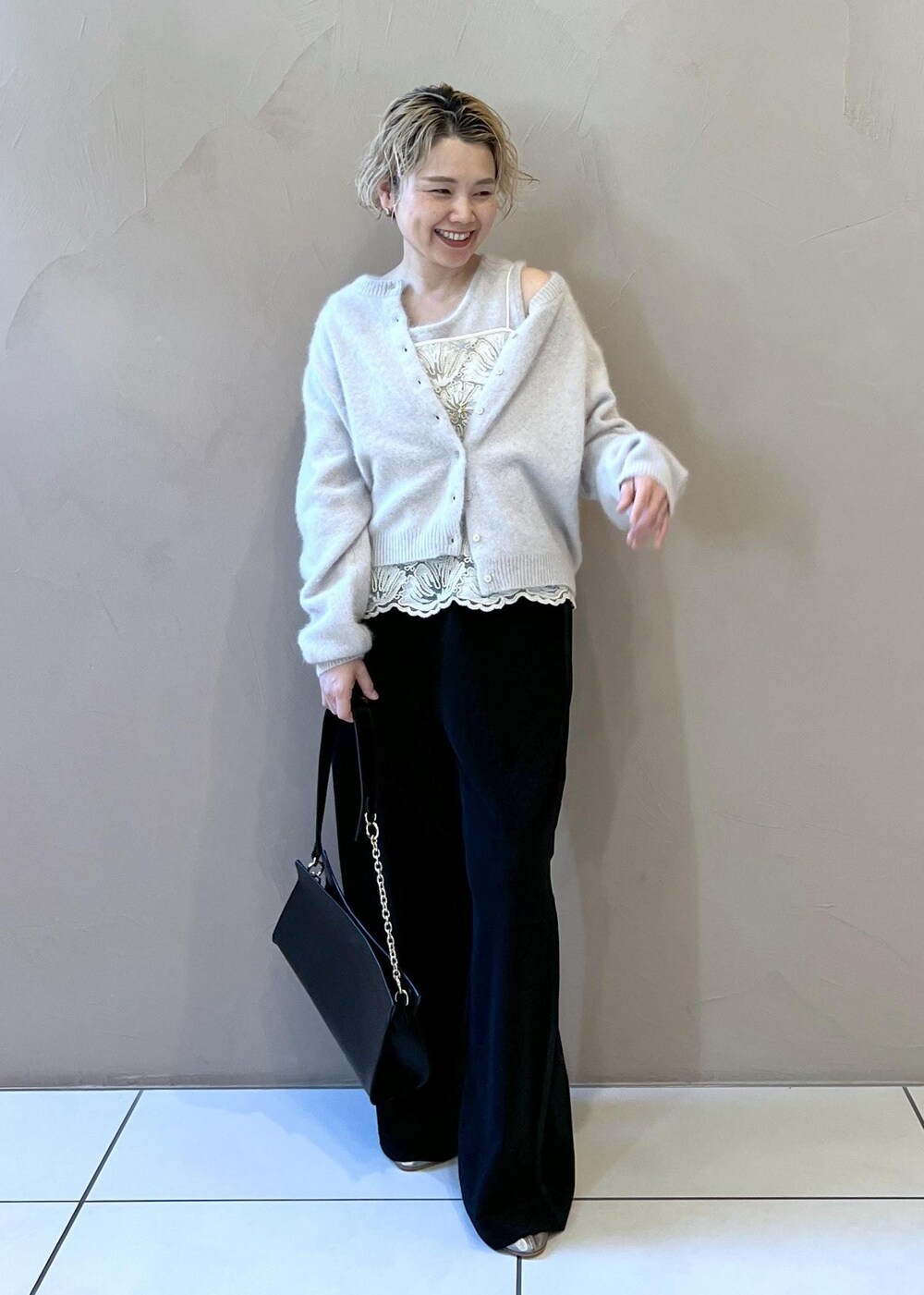 グレー系のタンクトップ、グレー系のカーディガン/ボレロ、ブラック系のショルダーバッグを着用したレディースの冬コーディネートの2枚目の写真