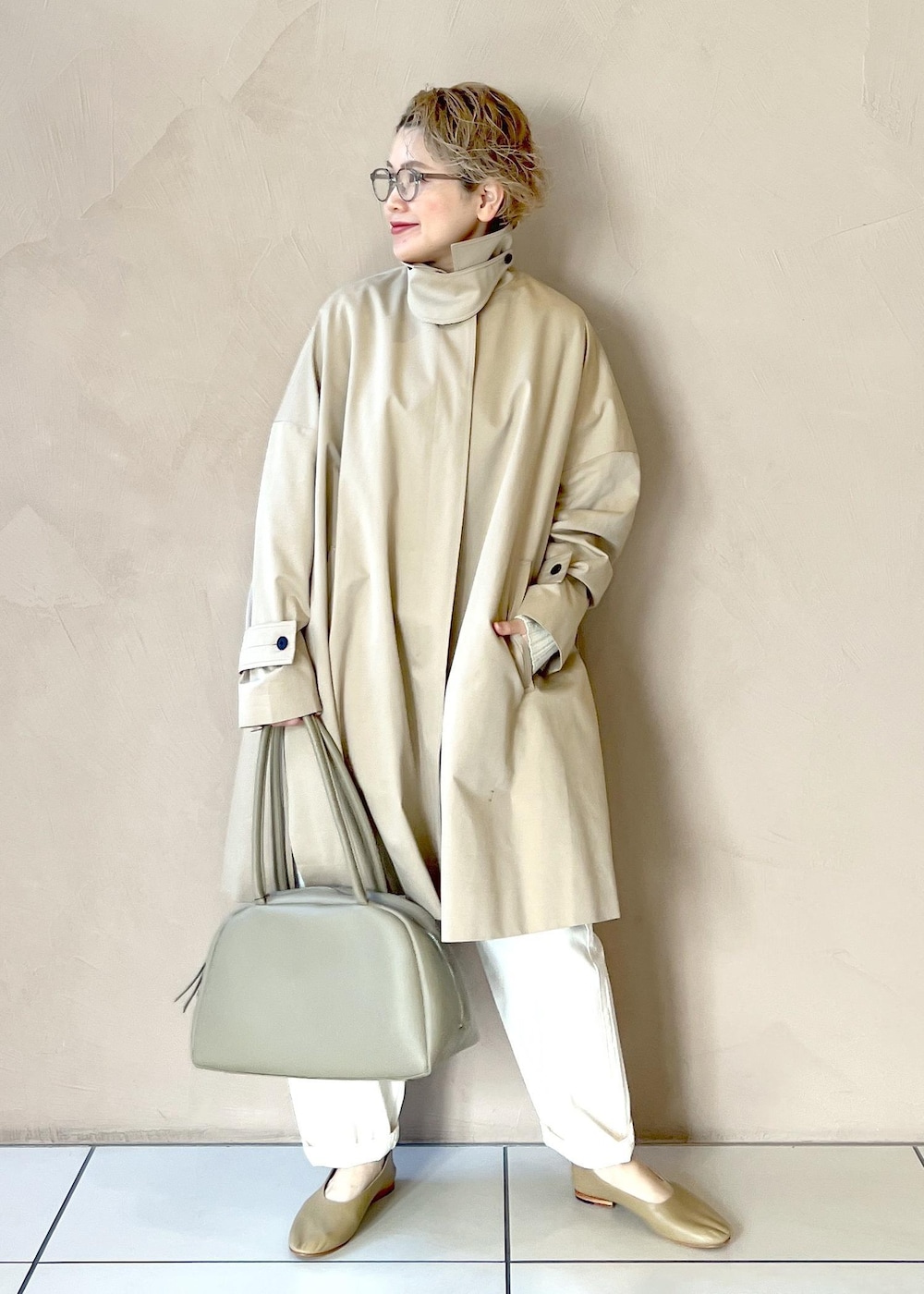 ホワイト系のニット/セーター、ベージュ系のステンカラーコート、ホワイト系のその他パンツを着用したレディースの冬コーディネートの2枚目の写真