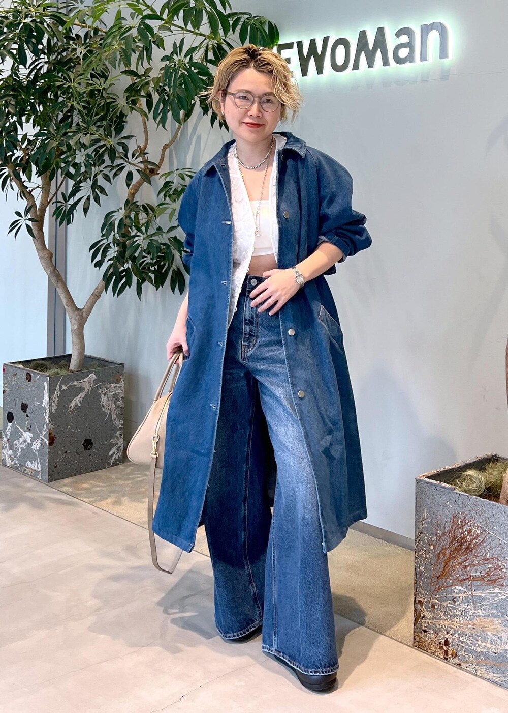 ベージュ系のボストンバッグ、ブルー系のデニムパンツ、ホワイト系のベストを着用したレディースの冬コーディネートの3枚目の写真