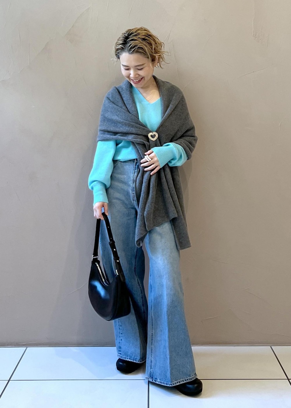 ブルー系のニット/セーター、ブルー系のデニムパンツ、ブラック系のスニーカーを着用したレディースの秋コーディネートの2枚目の写真