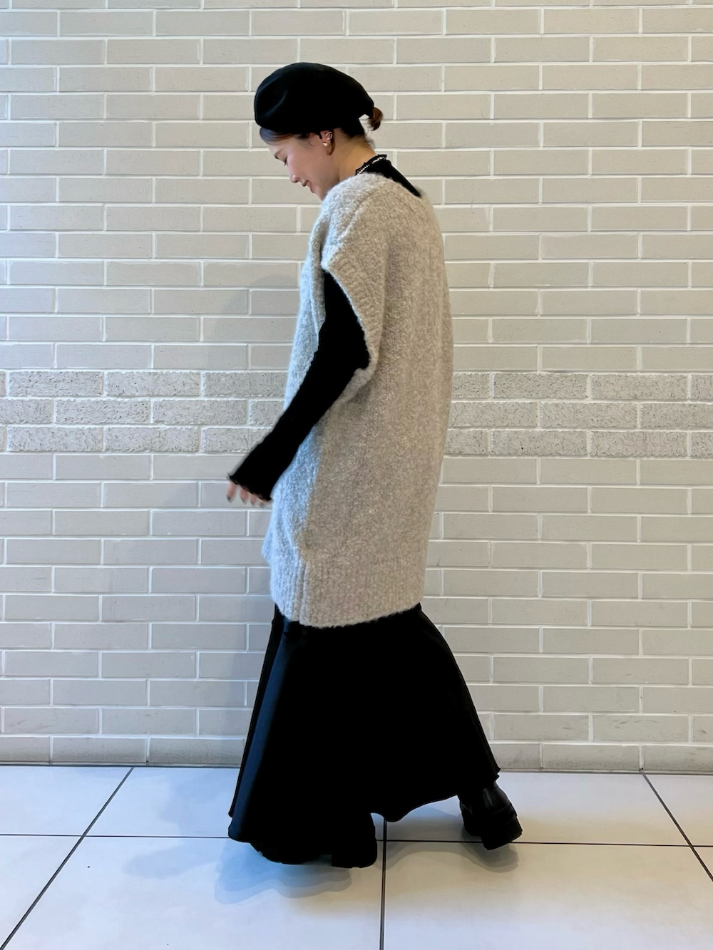 グレー系のニット/セーター、ブラック系のTシャツ/カットソー、ブラック系のスカートを着用したレディースの秋コーディネートの3枚目の写真