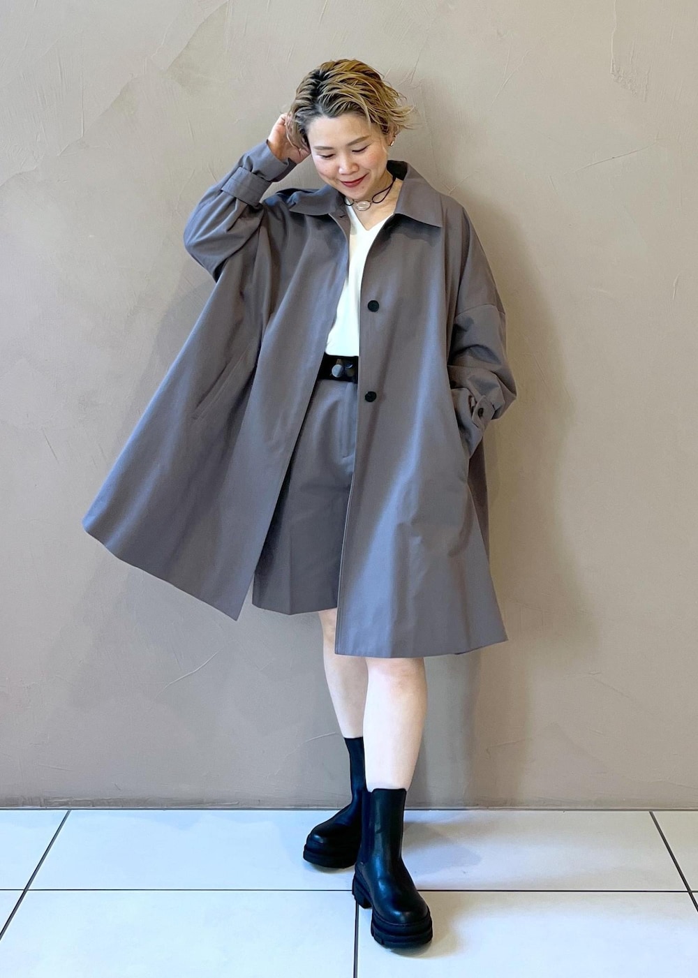 ブラック系のブーツ、ホワイト系のニット/セーター、グレー系のステンカラーコートを着用したレディースの冬コーディネートの2枚目の写真