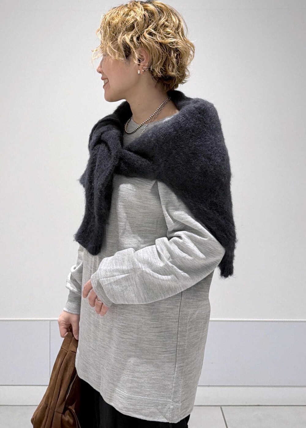 ブラック系のスカート、ブラウン系のハンドバッグ、ブラック系のブーツを着用したレディースの秋コーディネートの6枚目の写真