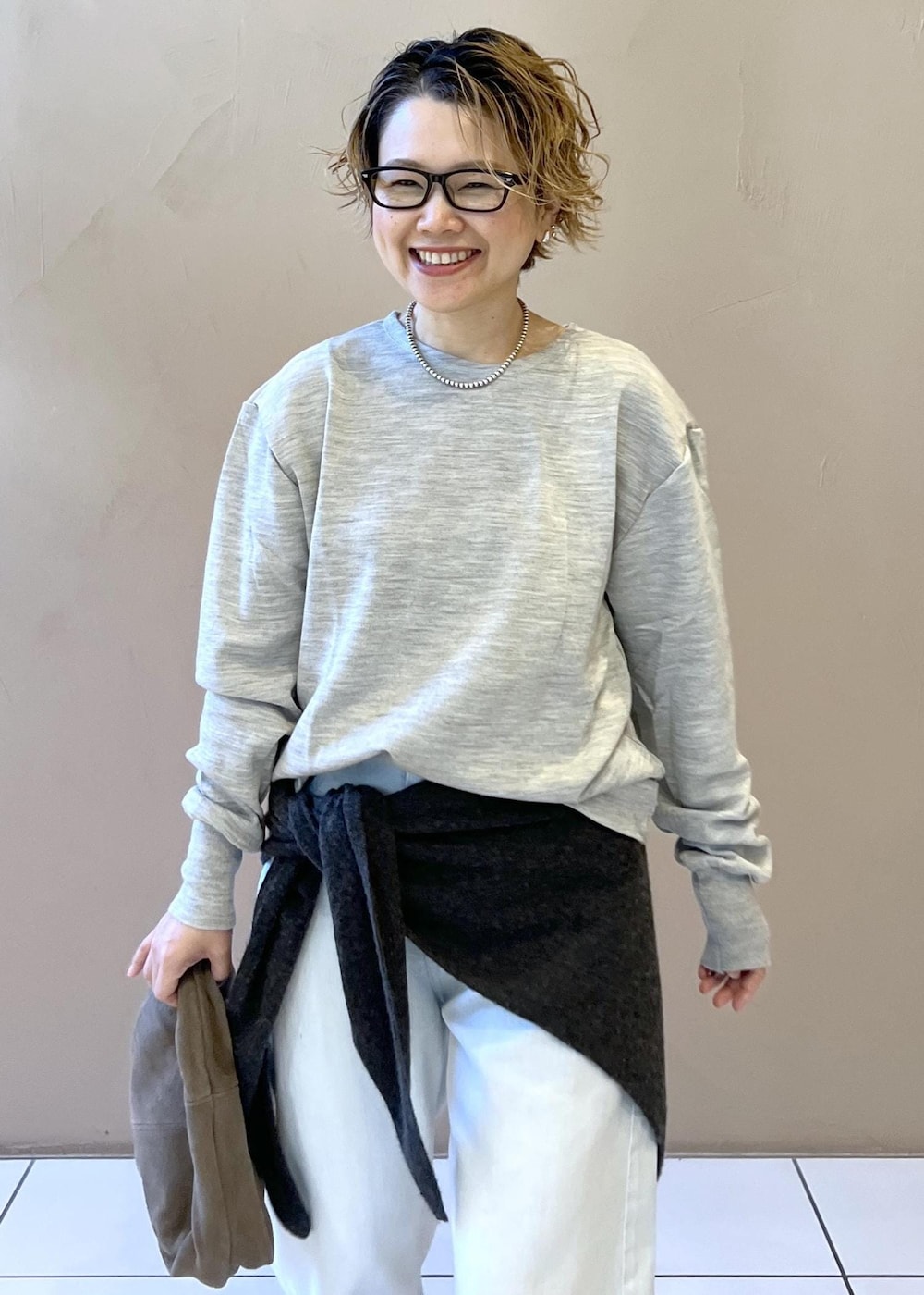 ブルー系のデニムパンツ、グレー系のハンドバッグ、ブラック系のパンプスを着用したレディースの秋コーディネートの5枚目の写真