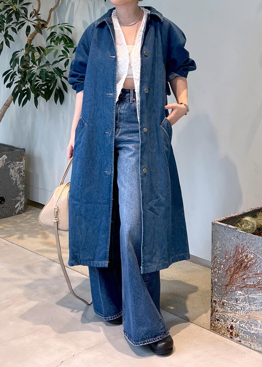 ベージュ系のボストンバッグ、ブルー系のデニムパンツ、ホワイト系のベストを着用したレディースの冬コーディネートの4枚目の写真