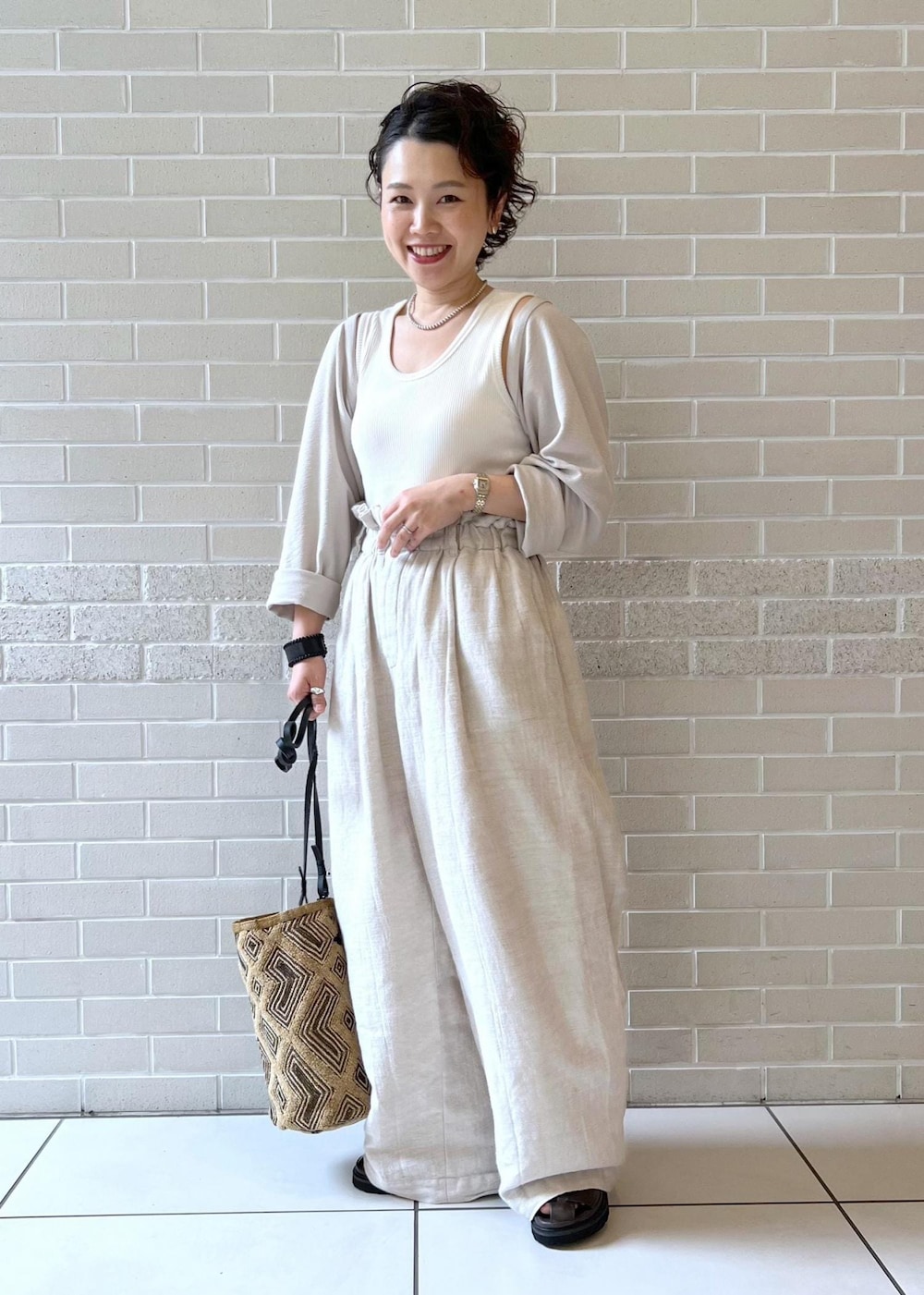 ブラウン系のサンダル、ホワイト系のカーディガン/ボレロ、ホワイト系のスラックスを着用したレディースの夏コーディネートの2枚目の写真