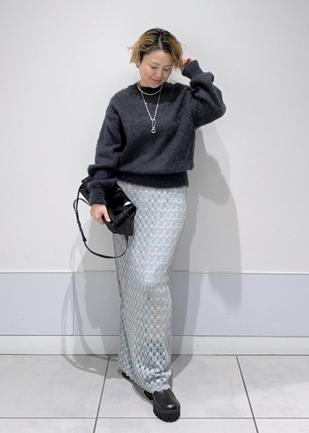 ブラック系のショルダーバッグ、グリーン系のスカート、ブラック系のブーツを着用したレディースの秋コーディネートの3枚目の写真