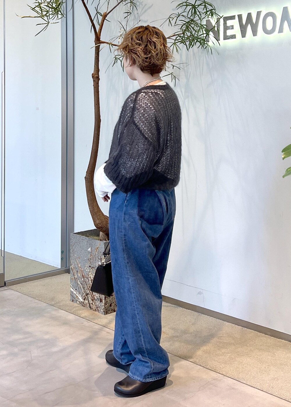 ブルー系のデニムパンツ、ブラック系のハンドバッグ、ブラック系のスニーカーを着用したレディースの秋コーディネートの5枚目の写真