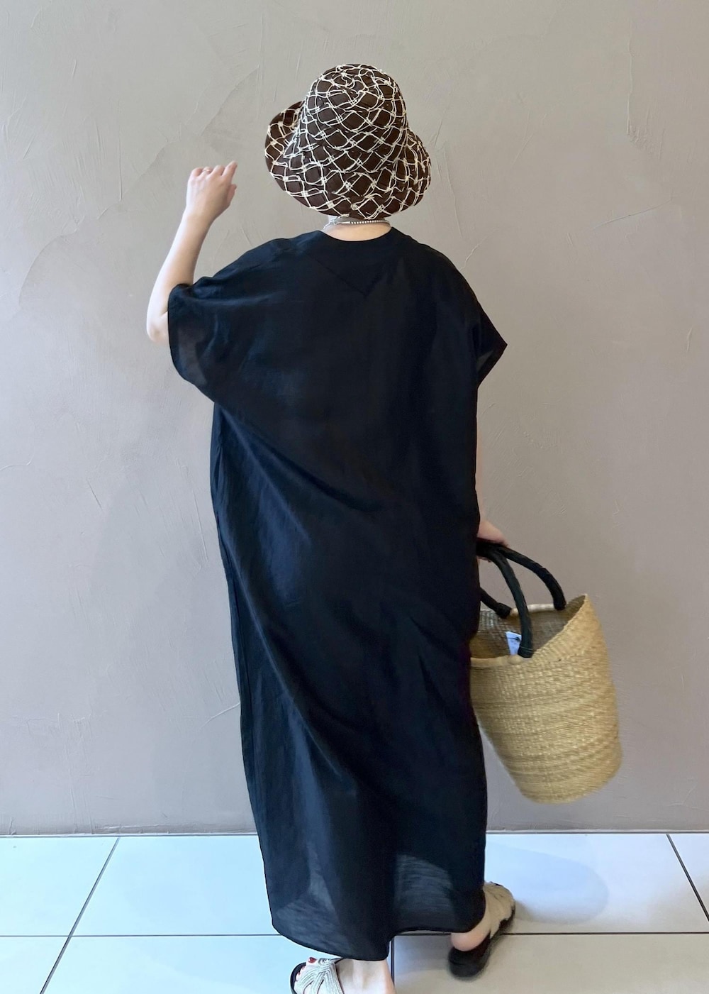 ゴールド系のサンダル、ブラック系のワンピース、ベージュ系のかごバッグを着用したレディースの夏コーディネートの6枚目の写真