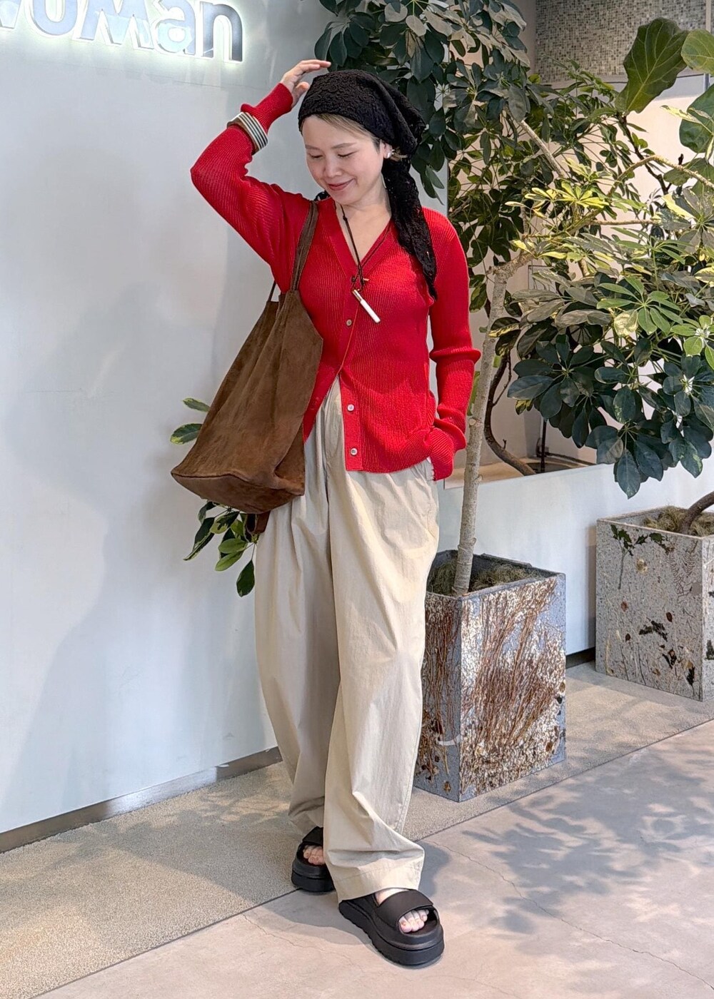 レッド系のカーディガン/ボレロ、ベージュ系のその他パンツ、ブラック系のサンダルを着用したレディースの春コーディネートの2枚目の写真