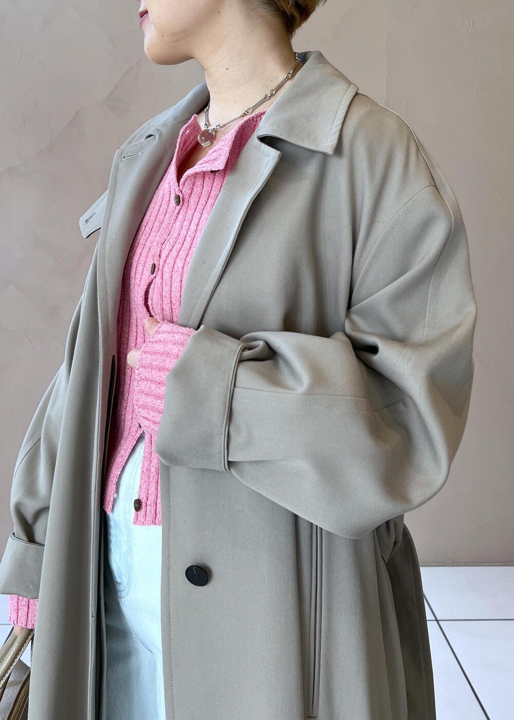 ベージュ系のボストンバッグ、ベージュ系のステンカラーコート、ブルー系のデニムパンツを着用したレディースの冬コーディネートの8枚目の写真