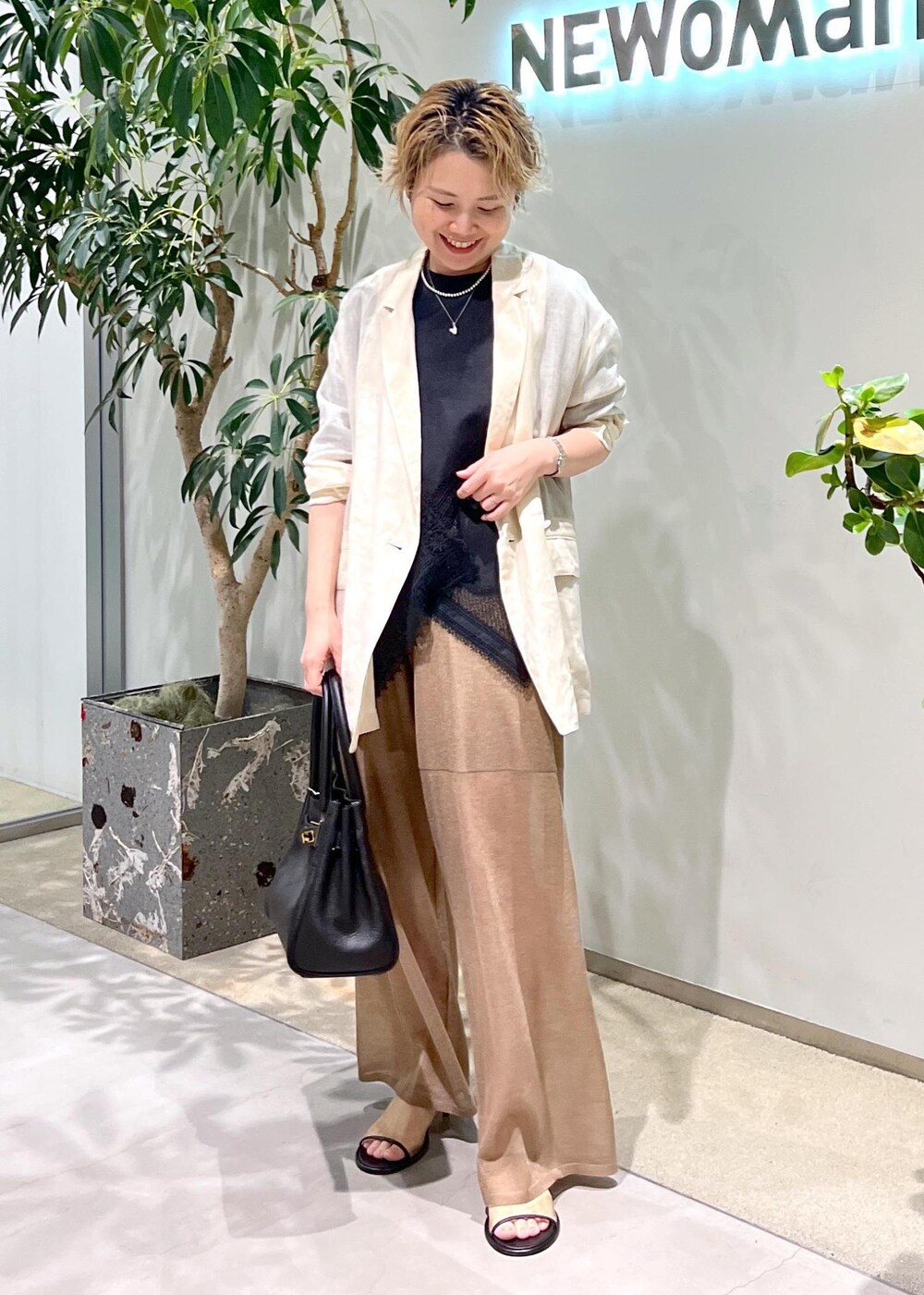 ブラック系のショルダーバッグ、ブラック系のTシャツ/カットソー、ホワイト系のテーラードジャケットを着用したレディースの夏コーディネートの2枚目の写真