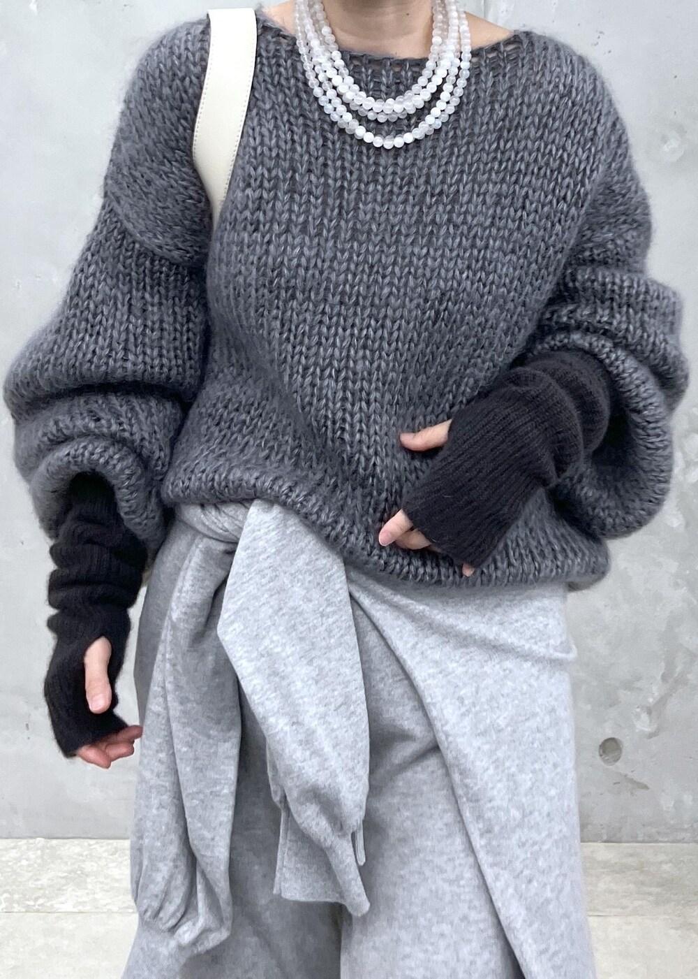 グレー系のニット/セーター、ホワイト系のボディバッグ/ウエストポーチ、グレー系の手袋を着用したレディースの秋コーディネートの7枚目の写真