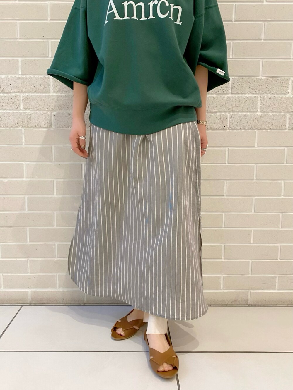 グリーン系のスウェット、ブラック系のワンピース、ブラウン系のサンダルを着用したレディースの春コーディネートの4枚目の写真