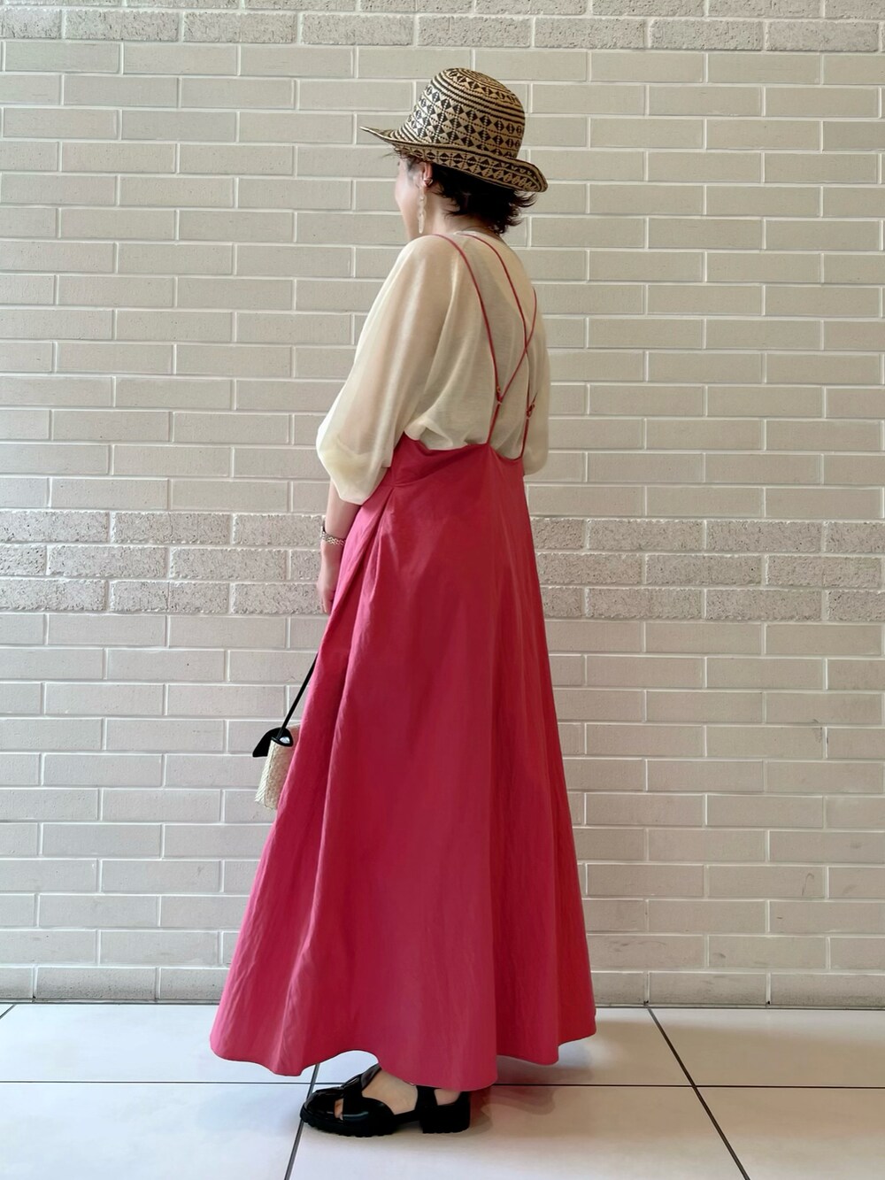 ピンク系のワンピース、ブラック系のショルダーバッグ、ブラック系のサンダルを着用したレディースの春コーディネートの3枚目の写真