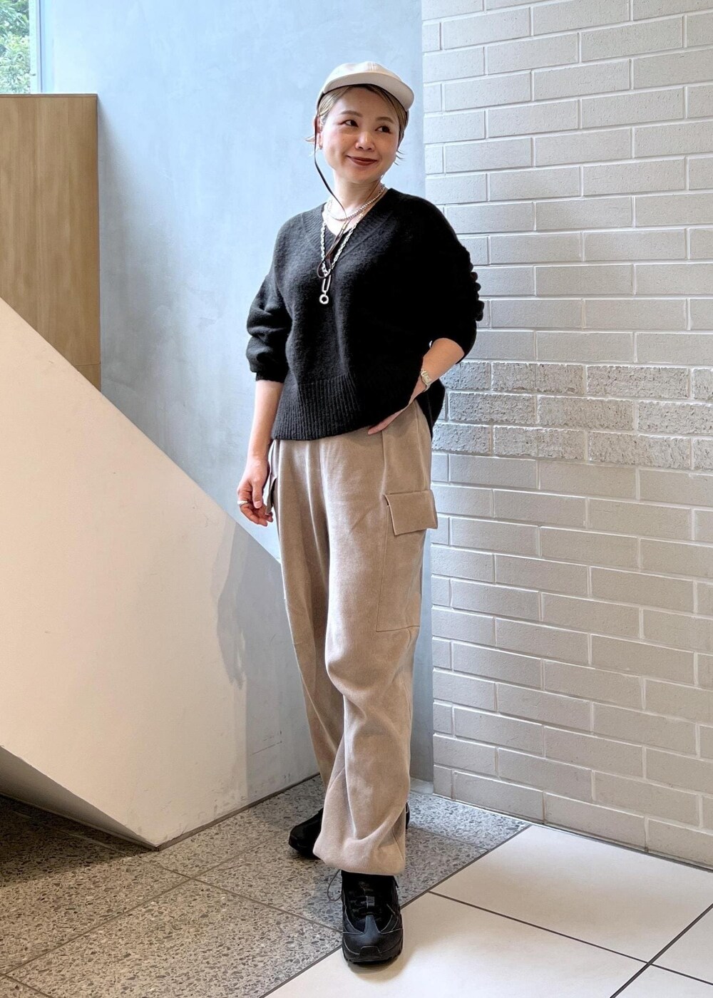 ホワイト系のピーコート、グレー系のカーゴパンツ、ブラウン系のニット/セーターを着用したレディースの秋コーディネートの2枚目の写真