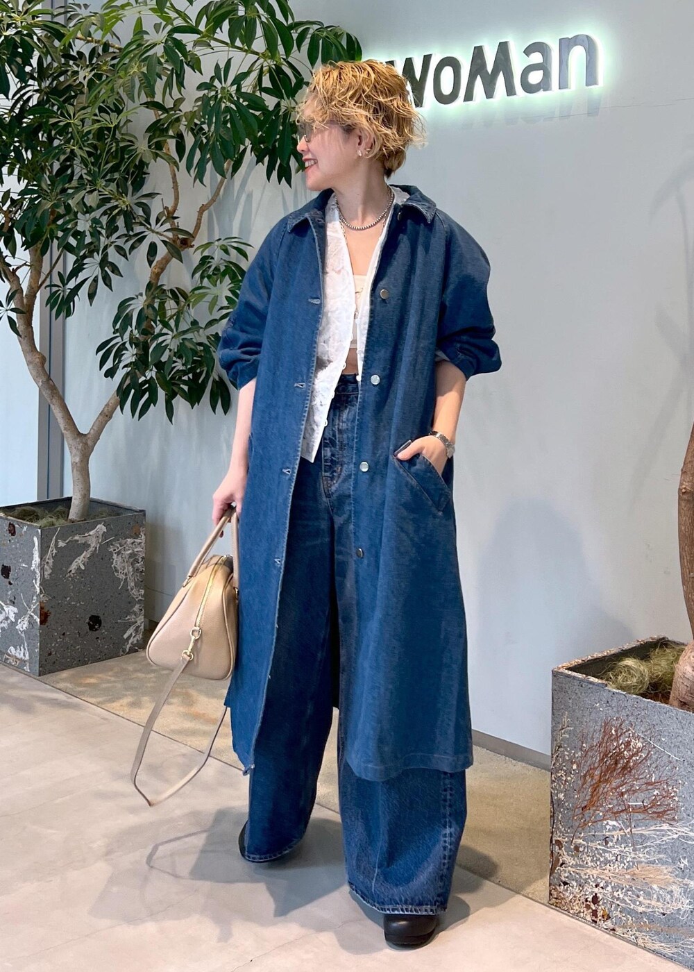 ベージュ系のボストンバッグ、ブルー系のデニムパンツ、ホワイト系のベストを着用したレディースの冬コーディネートの2枚目の写真