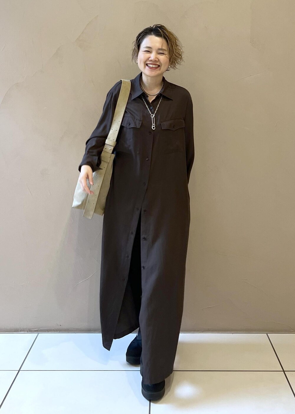 ベージュ系のショルダーバッグ、グレー系のワンピース、ブラック系のブーツを着用したレディースの秋コーディネートの2枚目の写真