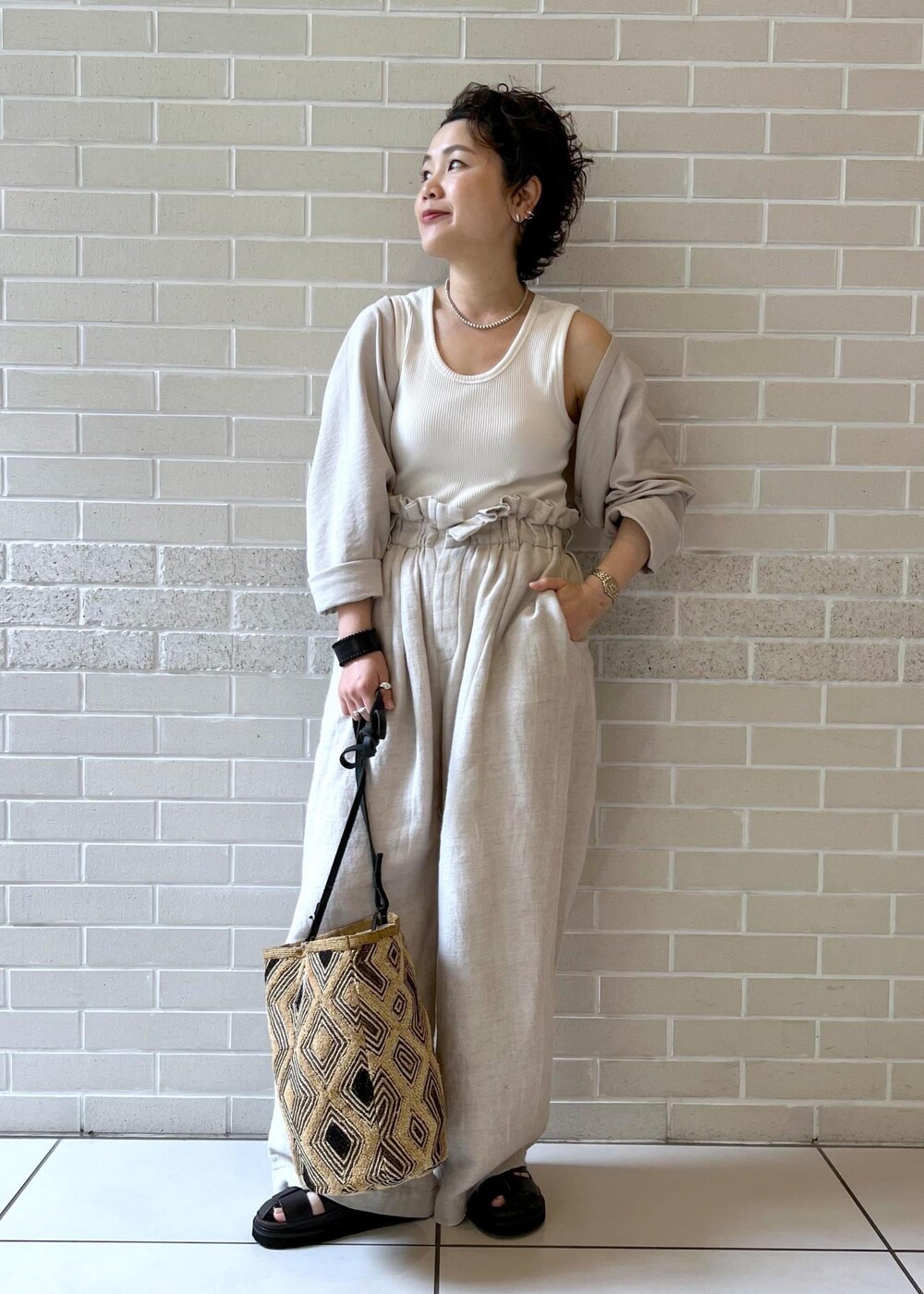 ブラウン系のサンダル、ホワイト系のカーディガン/ボレロ、ホワイト系のスラックスを着用したレディースの夏コーディネートの3枚目の写真