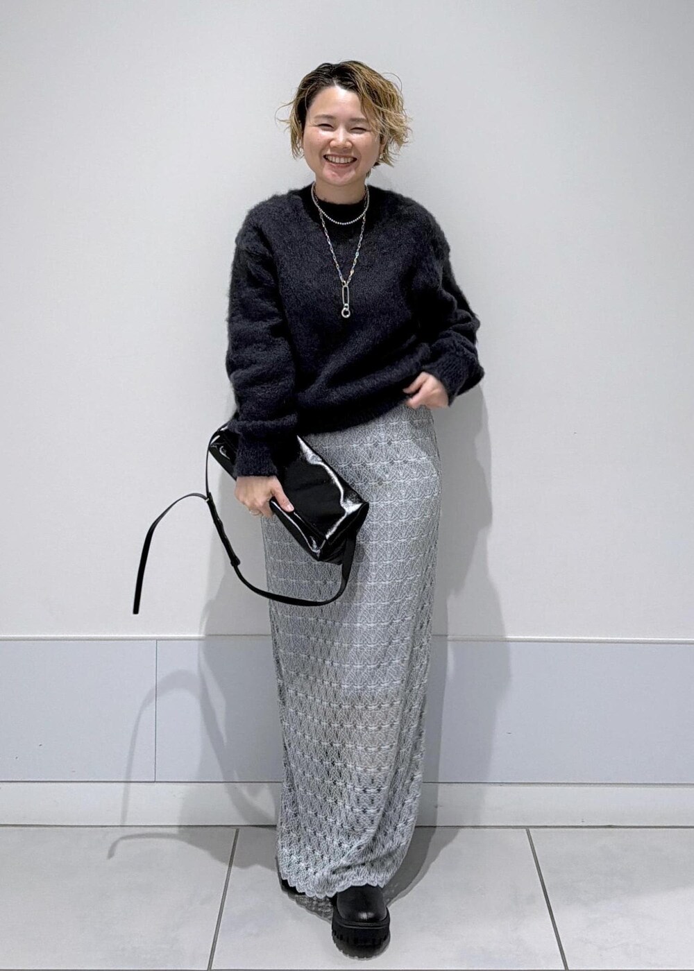 ブラック系のショルダーバッグ、グリーン系のスカート、ブラック系のブーツを着用したレディースの秋コーディネートの4枚目の写真