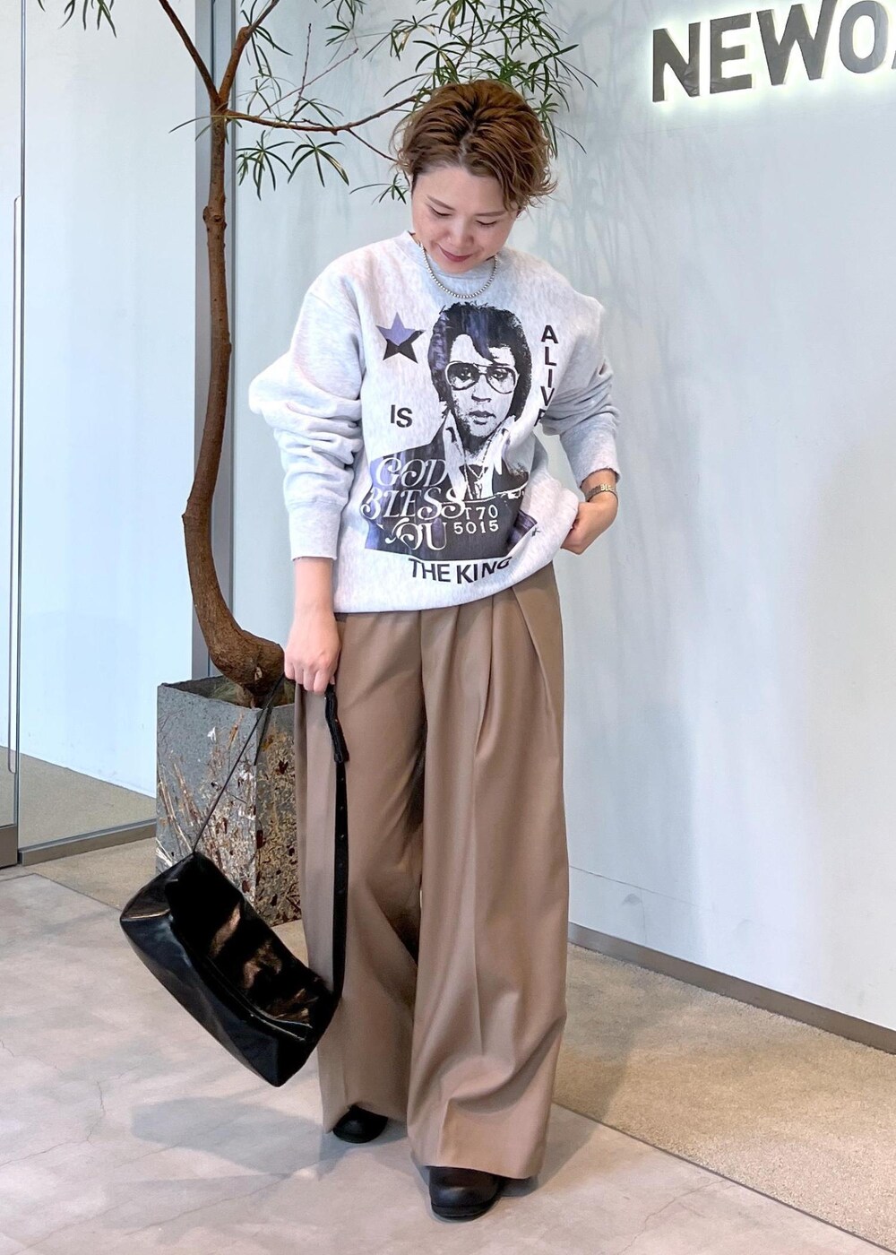 ベージュ系のスラックス、ブラック系のショルダーバッグ、ブラック系のスニーカーを着用したレディースの秋コーディネートの4枚目の写真