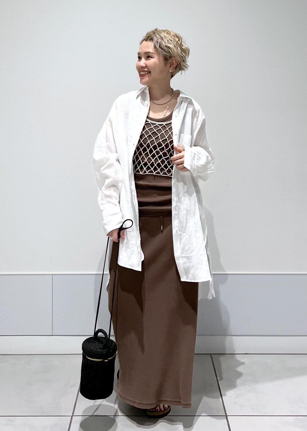 ブラック系のショルダーバッグ、ベージュ系のキャミソール、ブラウン系のタンクトップを着用したレディースの夏コーディネートの3枚目の写真