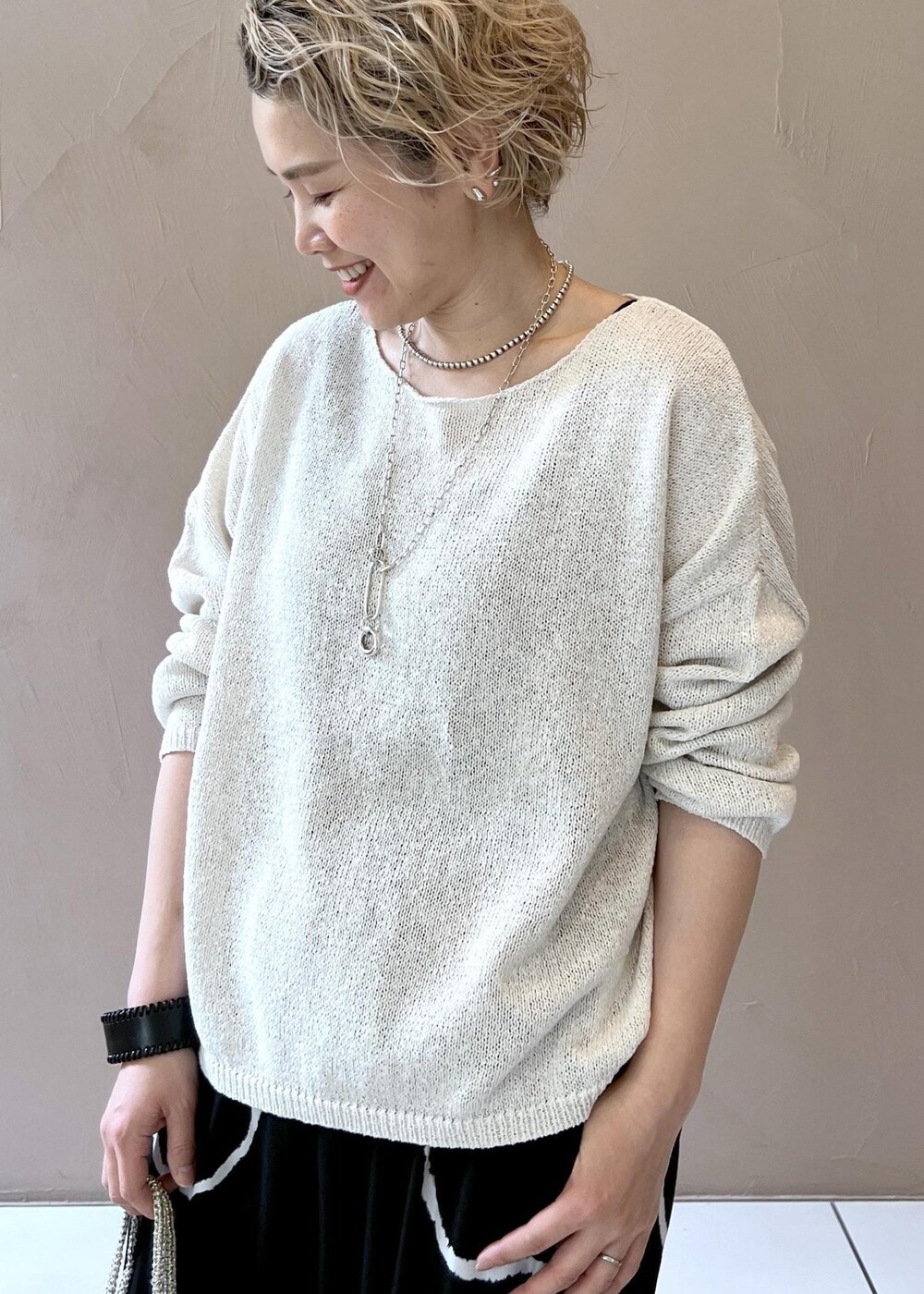 ゴールド系のハンドバッグ、シルバー系のサンダル、ホワイト系のニット/セーターを着用したレディースの春コーディネートの4枚目の写真