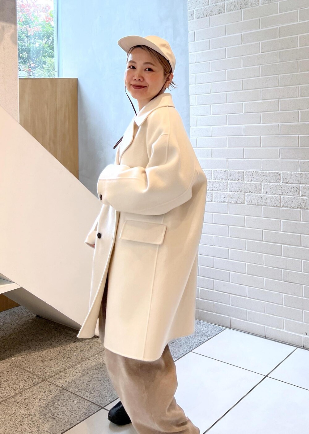 ホワイト系のピーコート、グレー系のカーゴパンツ、ブラウン系のニット/セーターを着用したレディースの秋コーディネートの9枚目の写真