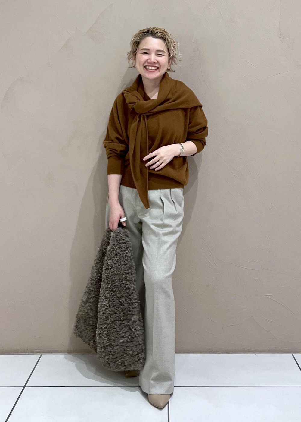 ベージュ系のスラックス、ブラウン系のトートバッグ、イエロー系のニット/セーターを着用したレディースの秋コーディネートの2枚目の写真