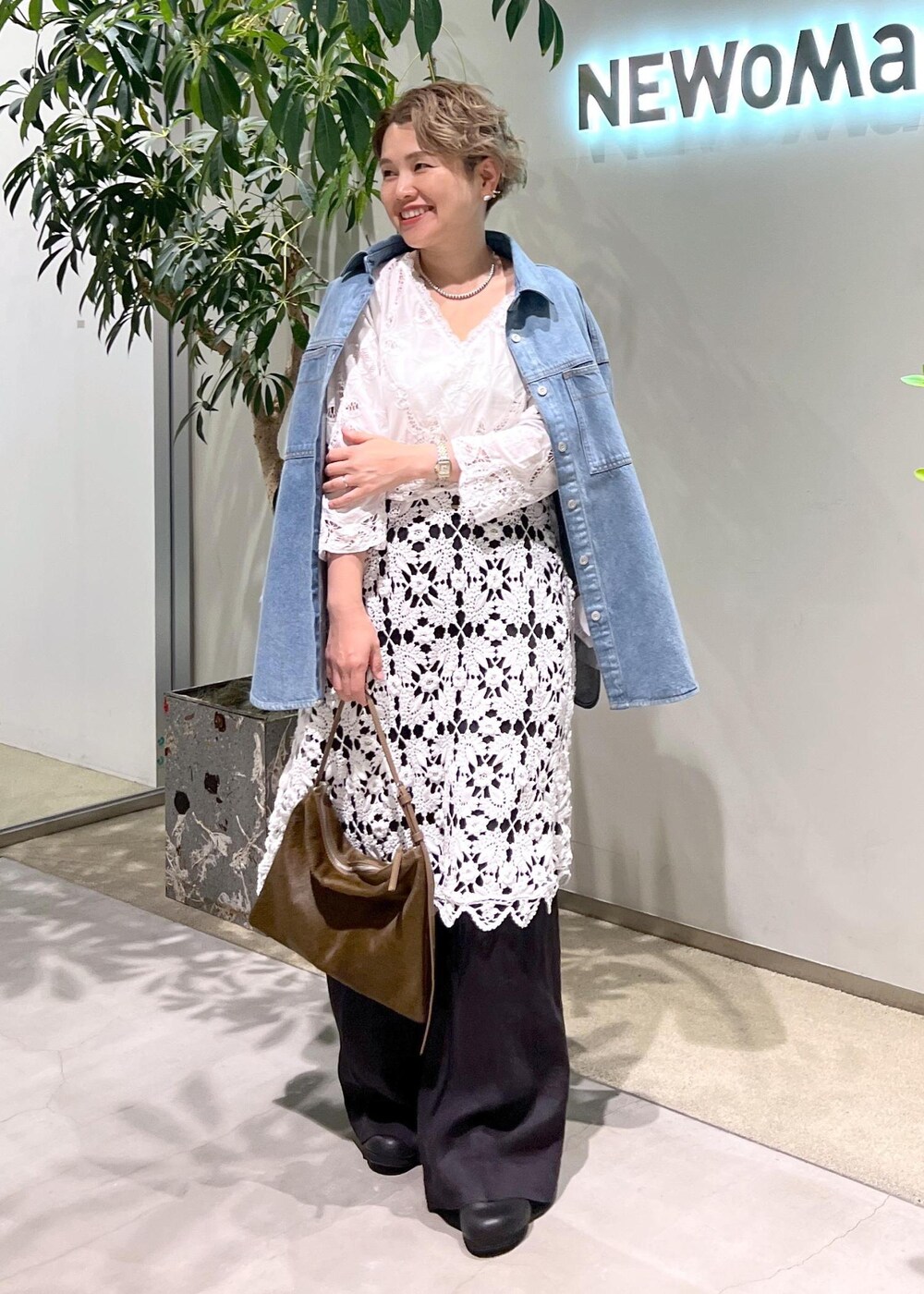 ブラック系のスラックス、ブルー系のシャツ/ブラウス、ブラウン系のショルダーバッグを着用したレディースの夏コーディネートの2枚目の写真