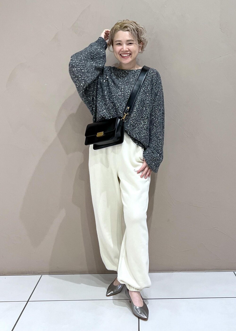 ホワイト系のスウェットパンツ、ブラック系のショルダーバッグ、シルバー系のパンプスを着用したレディースの秋コーディネートの2枚目の写真