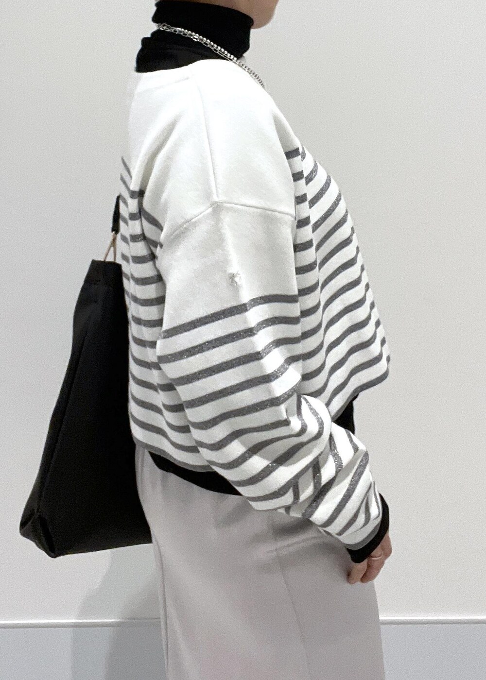 ブラック系のブーツ、ブラック系のTシャツ/カットソー、シルバー系のスカートを着用したレディースの冬コーディネートの7枚目の写真