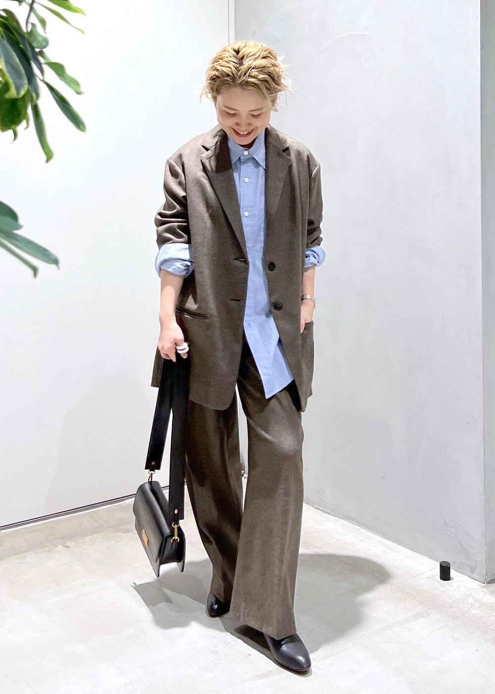 ブルー系のシャツ/ブラウス、ブラック系のショルダーバッグ、ブラウン系のスラックスを着用したレディースの秋コーディネートの3枚目の写真