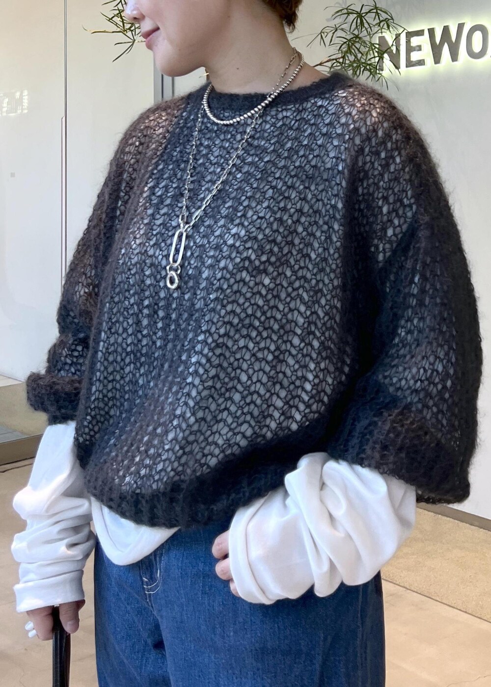 ブルー系のデニムパンツ、ブラック系のハンドバッグ、ブラック系のスニーカーを着用したレディースの秋コーディネートの6枚目の写真