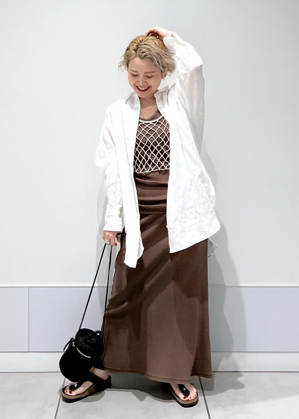 ブラック系のショルダーバッグ、ベージュ系のキャミソール、ブラウン系のタンクトップを着用したレディースの夏コーディネートの4枚目の写真