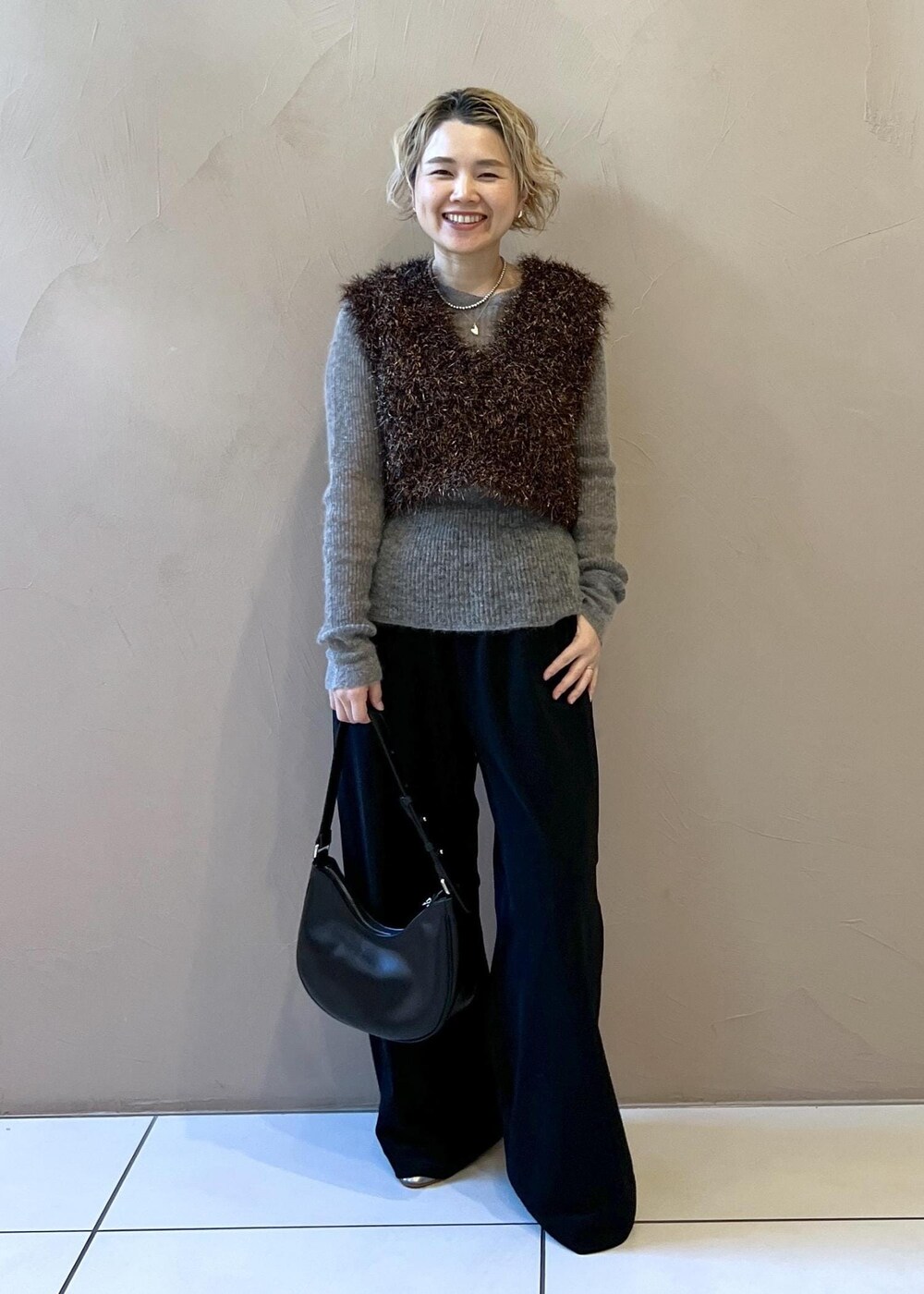 ブラック系のステンカラーコート、グレー系のニット/セーター、ブラック系のその他パンツを着用したレディースの冬コーディネートの4枚目の写真