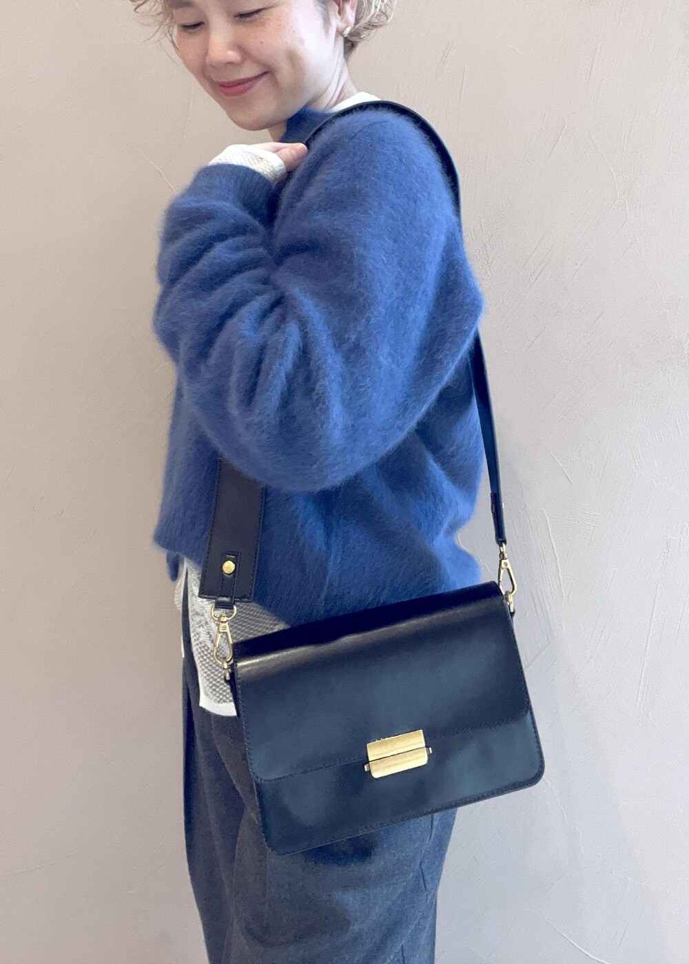 ブラック系のショルダーバッグ、ブルー系のカーディガン/ボレロ、グレー系のスラックスを着用したレディースの冬コーディネートの7枚目の写真