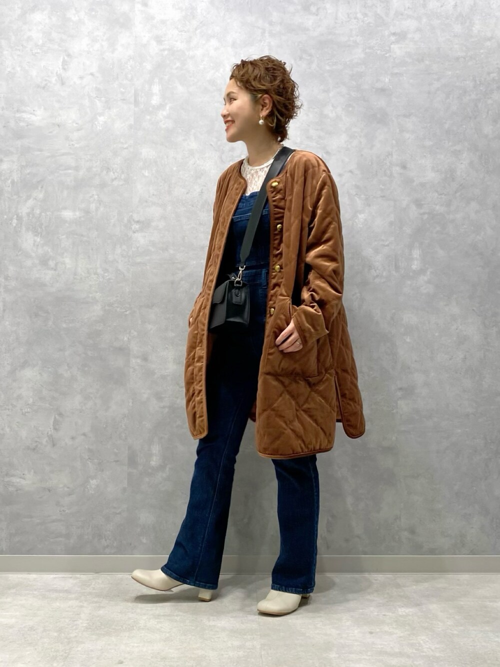 ブラウン系のブルゾン、ブルー系のサロペット/オーバーオール、ホワイト系のブーツを着用したレディースの秋コーディネートの2枚目の写真