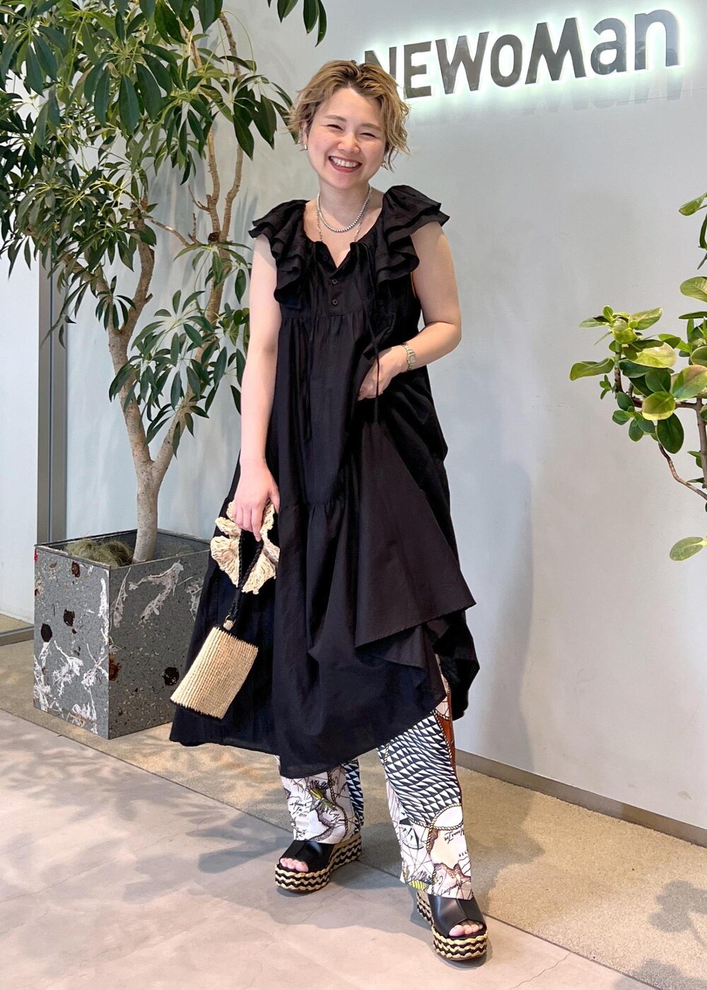 ブラック系のワンピース、ホワイト系のハンドバッグ、ブラック系のサンダルを着用したレディースの夏コーディネートの4枚目の写真