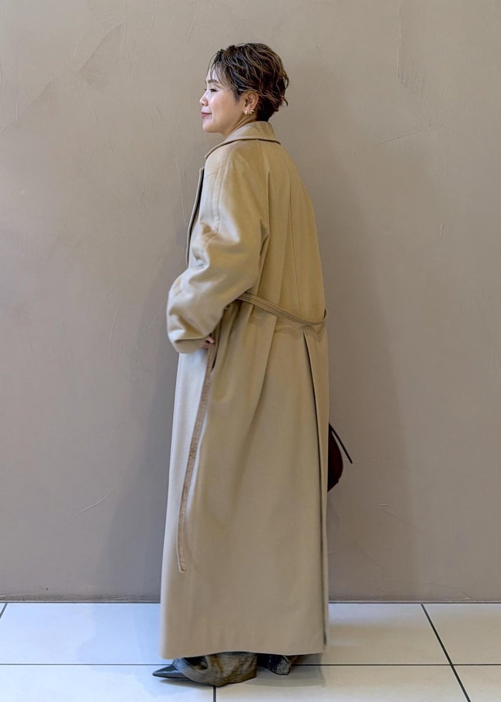 イエロー系のトレンチコート、ゴールド系のその他パンツ、ベージュ系のニット/セーターを着用したレディースの冬コーディネートの5枚目の写真