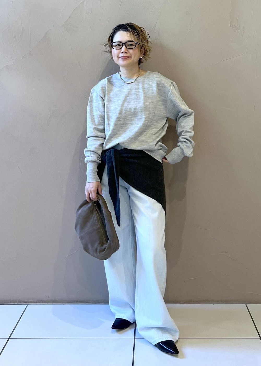 ブルー系のデニムパンツ、グレー系のハンドバッグ、ブラック系のパンプスを着用したレディースの秋コーディネートの4枚目の写真