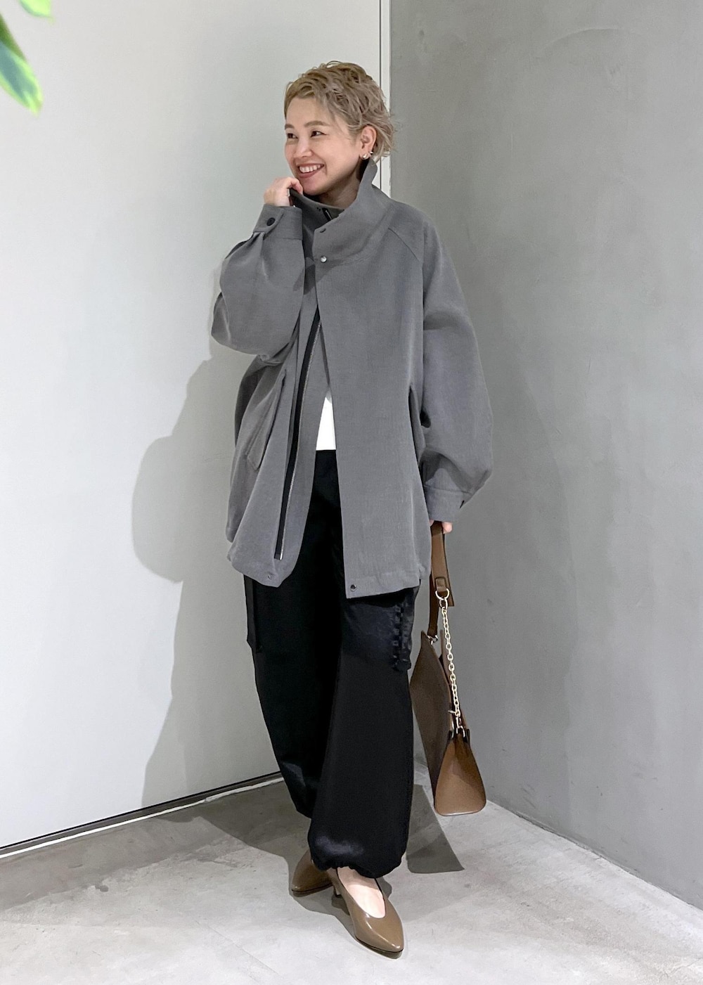 ブラウン系のショルダーバッグ、ブラック系のカーゴパンツ、ホワイト系のスウェットを着用したレディースの秋コーディネートの3枚目の写真